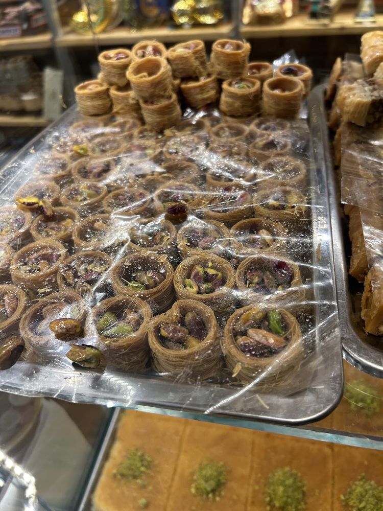 A full tray of cut pistachio baklava diamonds and fingers packed edge to edge.